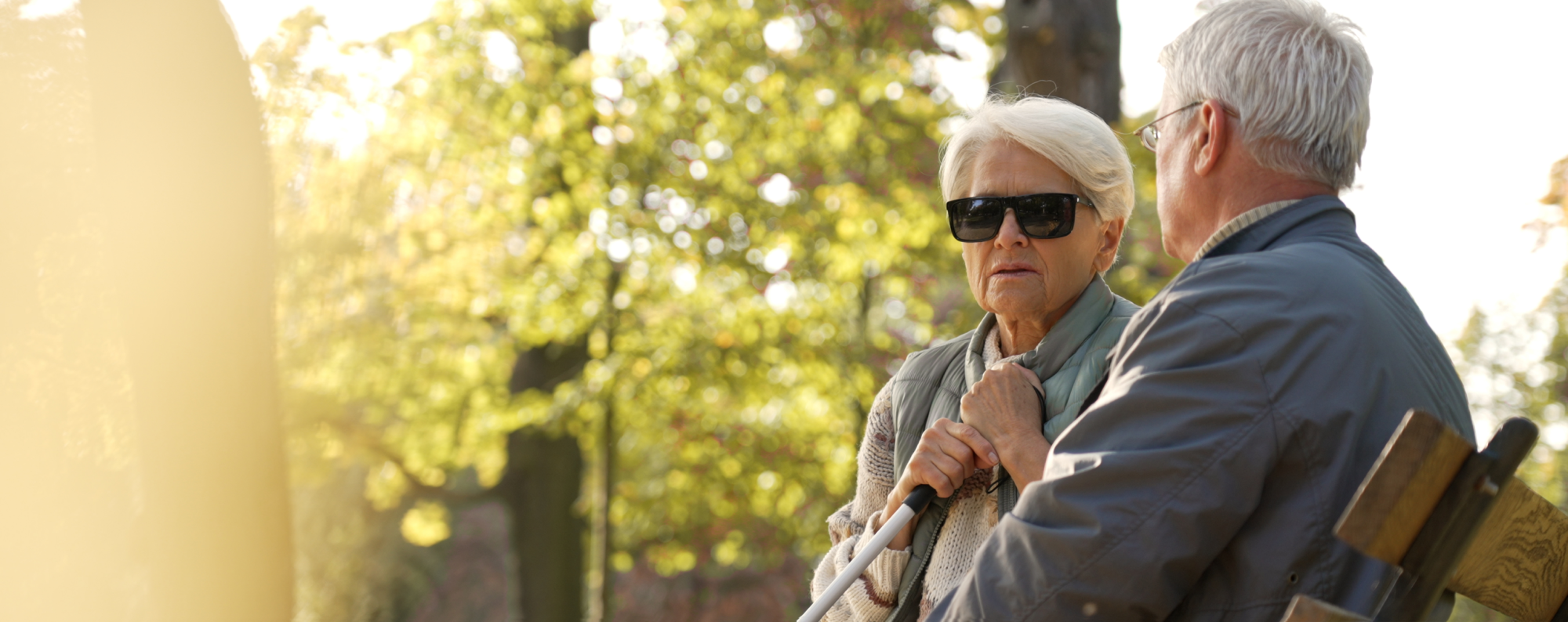 Two elderly blind people on a bench in the park