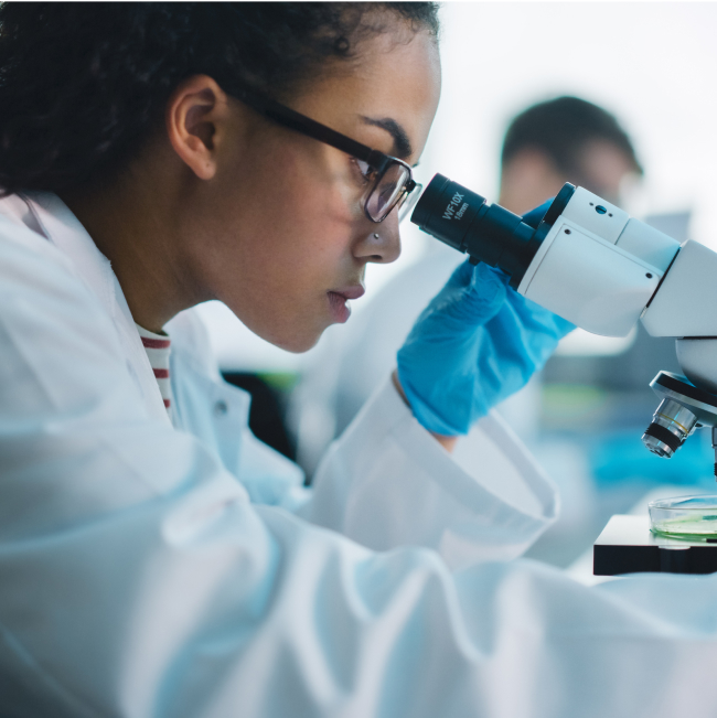 Female researcher looking through microscope in the lab