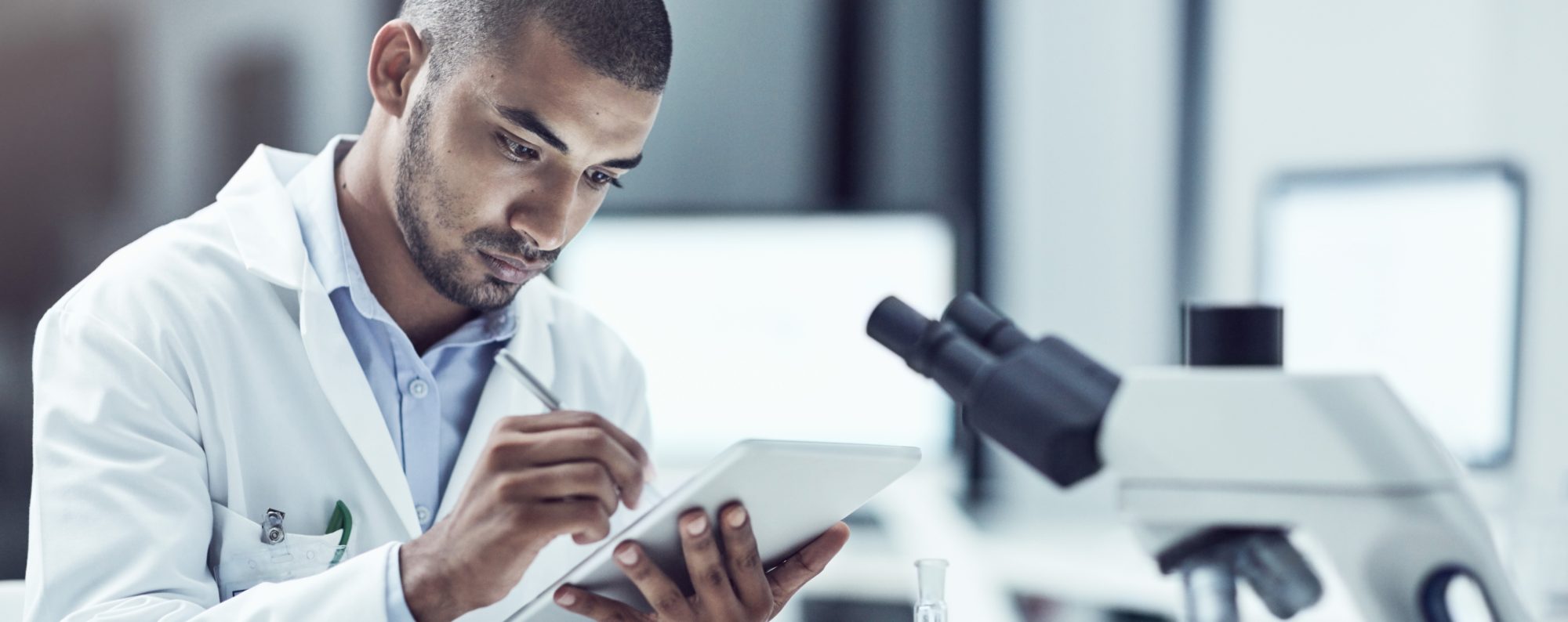 man in lab coat working on project with microscope