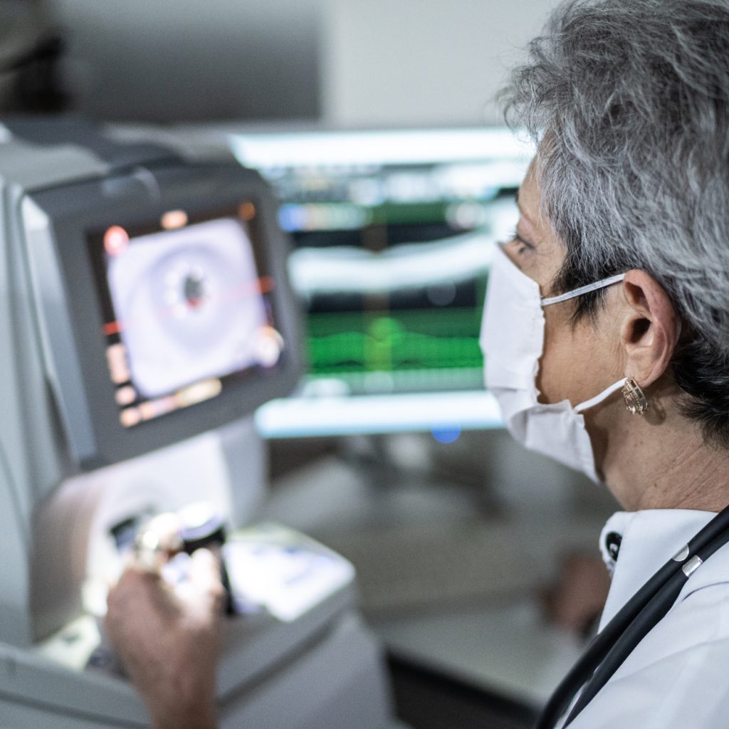 Researcher wearing PPE mask looking at test results on lab machine