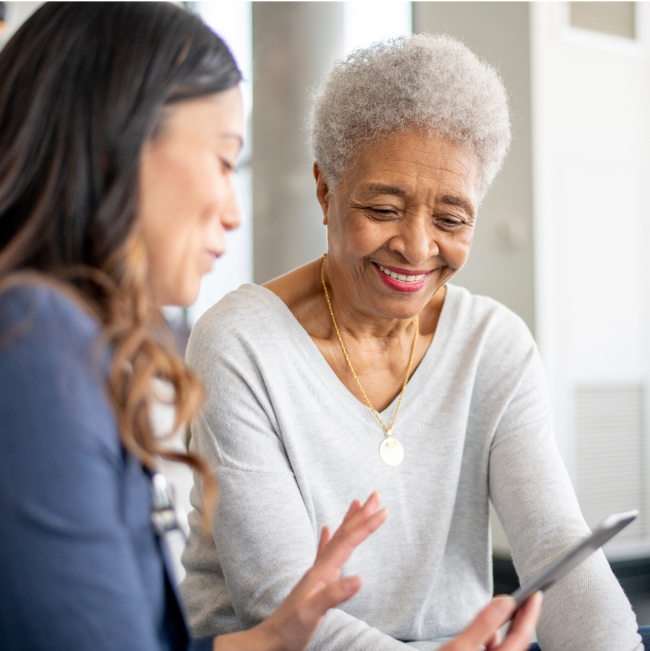 Elderly woman smiling while talking to younger woman