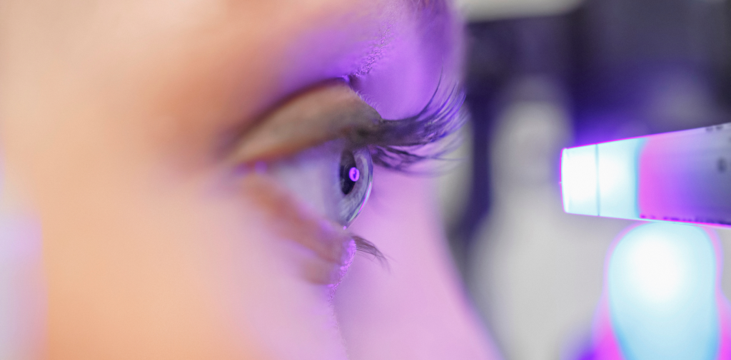 close-up of blue eye with purple light reflection, in profile